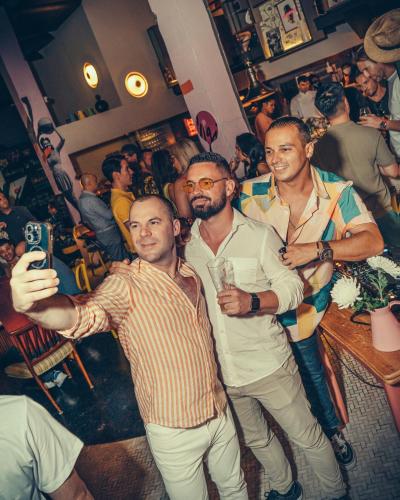 a group of men standing in a crowd in a bar at Sacha's Hotel Uno in Bangkok