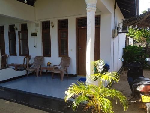 a porch of a house with chairs and a table at Aaliya Bay in Arugam Bay