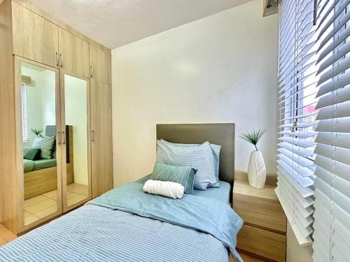 a bedroom with a bed with blue sheets and a mirror at Two Bedroom at One Spatial Iloilo in Iloilo City