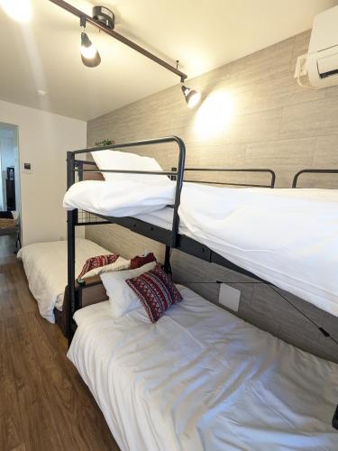two bunk beds in a room with white sheets at -Summer Escape- Just 15 min from Haneda Airport, Max 3 in Tokyo