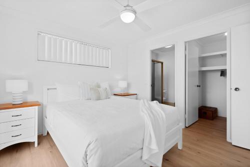 Un dormitorio blanco con una cama blanca y un espejo. en Bailey's Beach House, en East Ballina