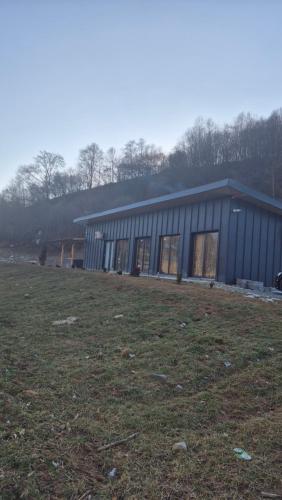 a large building with a field in front of it at Cabana Bendis in Suciu de Sus