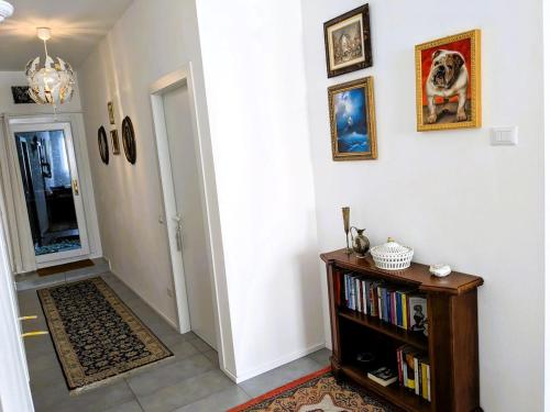 a hallway with a book shelf and pictures on the wall at Beautiful new apartment with private entrance and parking 5 min walking from center in Bellano