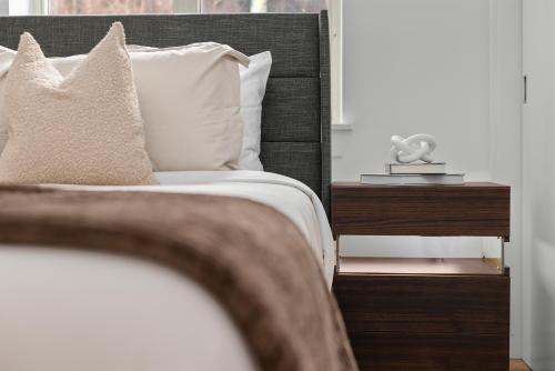 a bed with white sheets and pillows next to a window at Modern 2BR Steps from New York's Iconic Broadway in New York