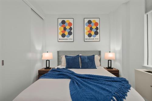 a white bedroom with two lamps and a bed at Modern 2BR Steps from New York's Iconic Broadway in New York