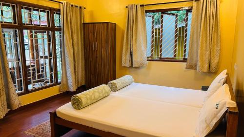 a bed in a room with two windows at Tamarind Tree Masinagudi in Masinagudi
