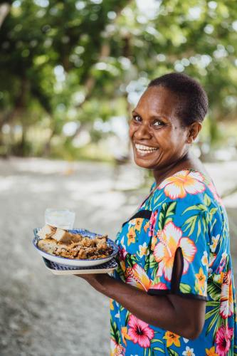 a woman is holding a plate of food at South Pacific Memories in Port Vila