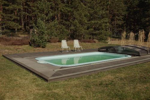 a swimming pool with two lawn chairs and a swimming pool at Berti in Upesgrīva