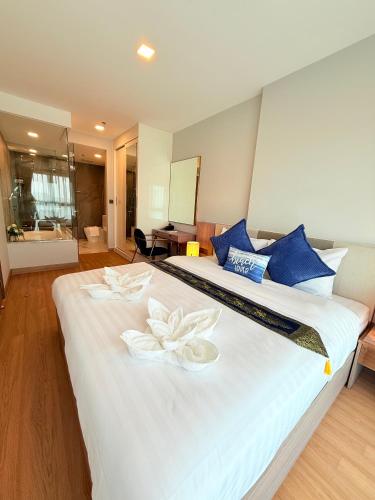 two beds in a hotel room with two flowers on them at The Astra Sky River Chiang Mai 三卧两卫宜居6人 无边泳池 热水浴缸 乳胶床垫 in Chiang Mai