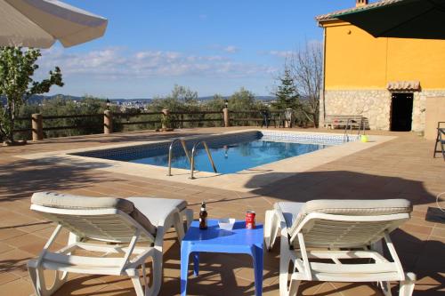 un patio con 2 sillas, una mesa y una piscina en Casa Escalona, en Ronda