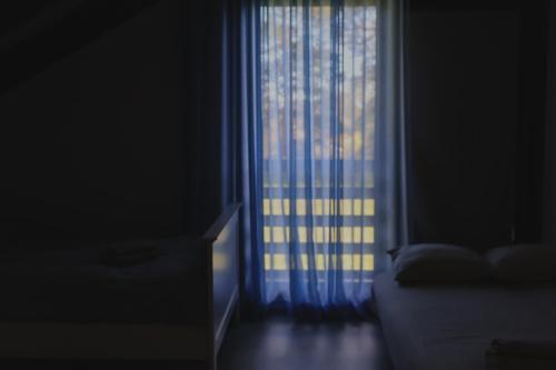 a room with a window with a bed and a curtain at Berti in Upesgrīva