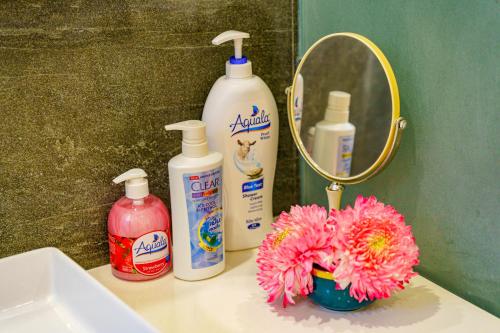 a sink with a mirror and a pink flower on a counter at HA Gateway Inn Hoian Priavate Pool Villa in Hoi An