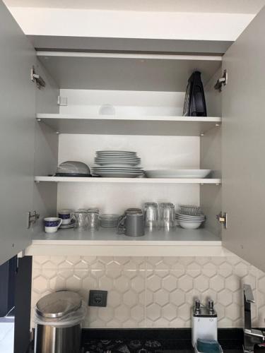 a kitchen with white shelves with dishes on them at Begonvil Life in Gazipasa