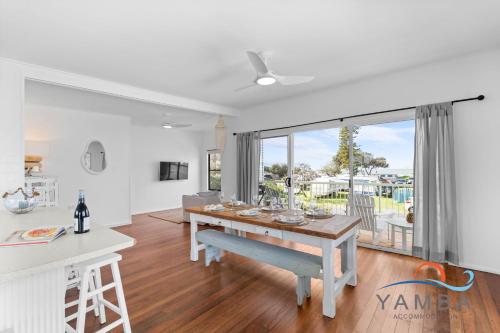 une cuisine et une salle à manger avec une table et une grande fenêtre dans l'établissement Stella LJHooker Yamba, à Brooms Head