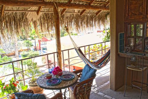 a table and chairs on a balcony with a hammock at The Bungalows Hotel in Cabo San Lucas