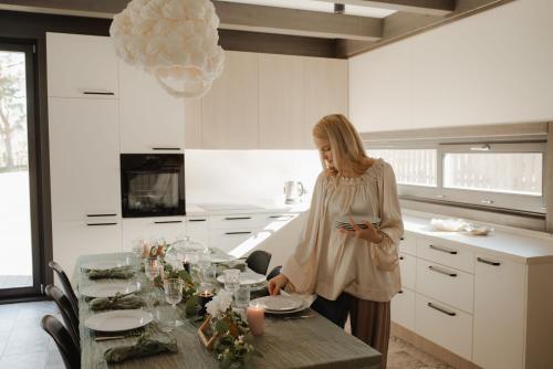 a woman standing in a kitchen with a table at Berti in Upesgrīva