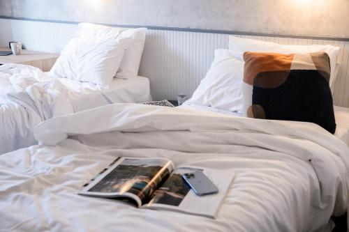a white bed with a book and a cell phone on it at Hotel TOTTO Wollongong in Wollongong