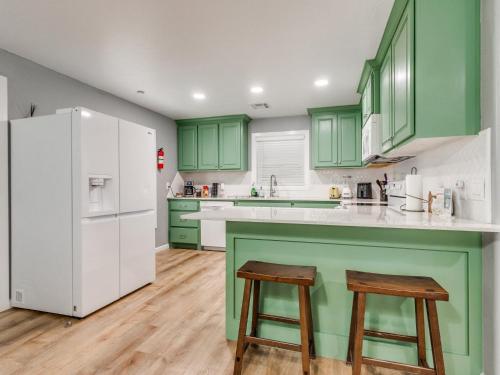 a kitchen with green cabinets and a white refrigerator at OKC Casita - Private Hot Tub, Fenced Yard, Mins to Top Spots, Pet friendly in Oklahoma City