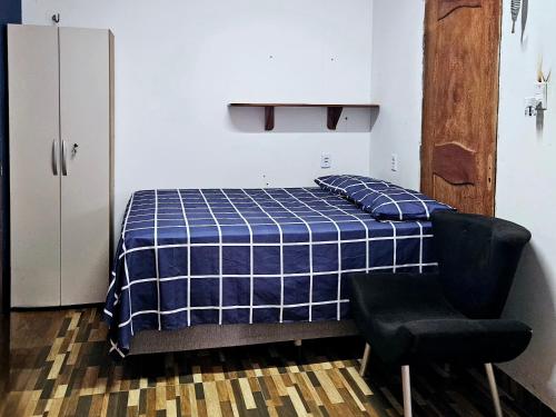 a bedroom with a bed and a black chair at Hospedaria Caripí in Barcarena