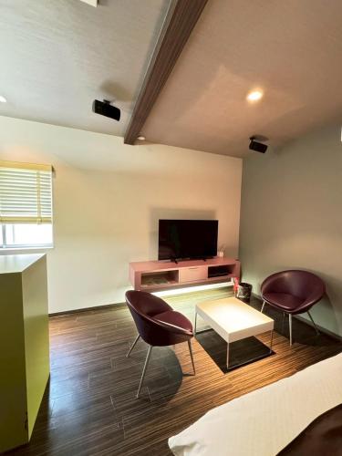 a living room with two chairs and a tv at Hotel JOYCE in Saijō-chō