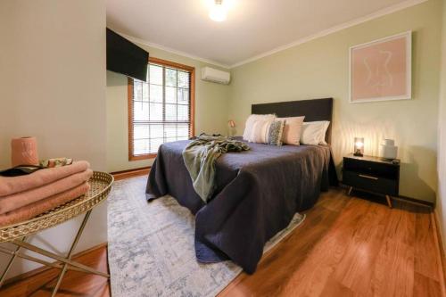 Un dormitorio con una cama y una mesa y una ventana. en Hideaway at Hepburn, en Hepburn Springs