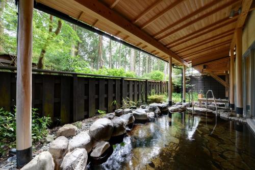 a house with a pond with rocks and a wooden ceiling at Diamond Hakone Society in Hakone