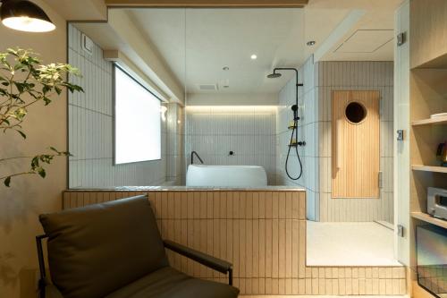 a bathroom with a tub and a sink in a room at etoe Hotel Shinjuku in Tokyo