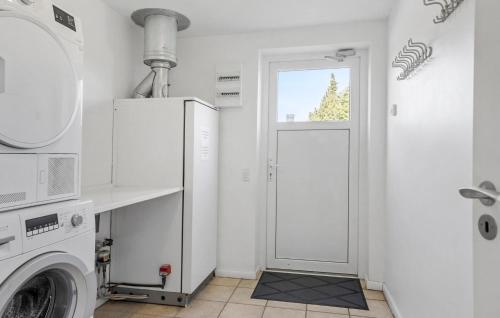 a white laundry room with a washing machine and a door at Stunning Home In Væggerløse With Wifi in Marielyst