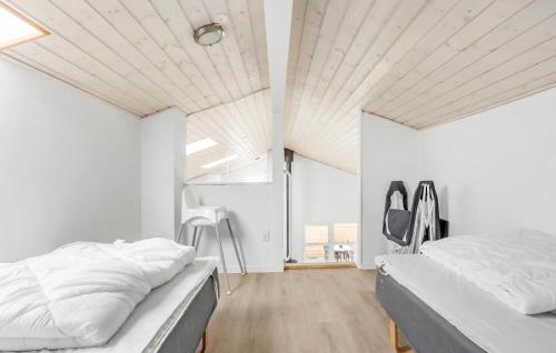 two beds in a bedroom with white walls and wood floors at Stunning Home In Væggerløse With Wifi in Marielyst