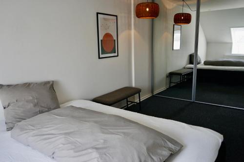 a bedroom with a white bed and a mirror at Central og rummelig lejlighed i Vejle in Vejle