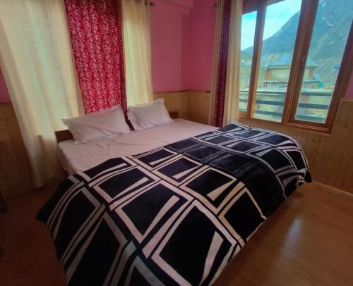 a bed in a room with a large window at Rupi Rani Home Stay in Gushāl
