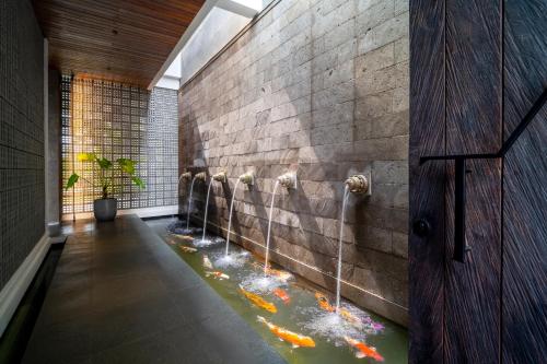 une pièce avec une fontaine à eau dans un mur avec dans l'établissement The Line Villas Canggu, à Canggu