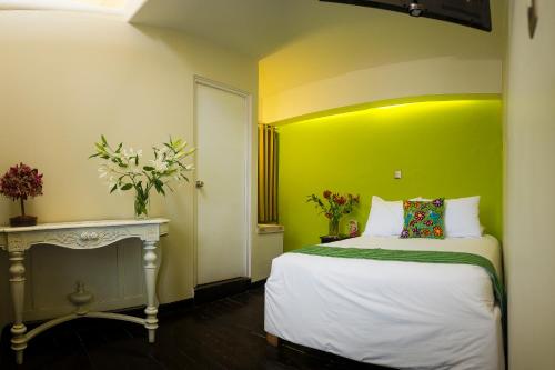 a bedroom with a bed and a green wall at Wakapunku Boutique Hotel in Cusco
