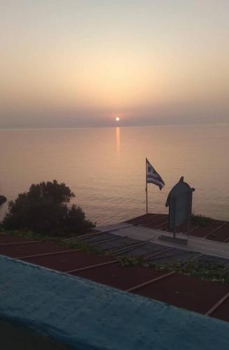 a view of the ocean at sunset with a flag at Delfini in Akhladherí