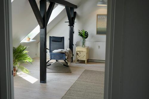 a hallway with a blue chair and an attic at Penthouselejlighed midt i Vejle in Vejle