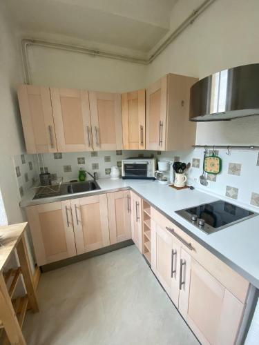 - une cuisine avec des comptoirs blancs et des armoires en bois dans l'établissement Joli cocon au cœur du Verdon, à Gréoux-les-Bains