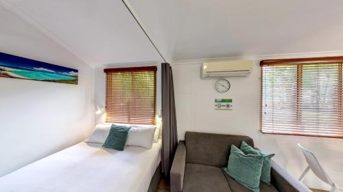 a small bedroom with a bed and a chair at BIG4 Adventure Whitsunday Resort in Airlie Beach