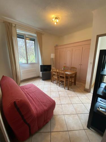 un salon avec une table et un canapé rouge dans l'établissement Joli cocon au cœur du Verdon, à Gréoux-les-Bains