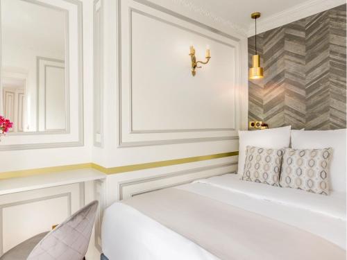 Cette chambre blanche comprend un lit et un miroir. dans l'établissement Merveil - Luxury Suite - Louvre -Sebastopol I, à Paris