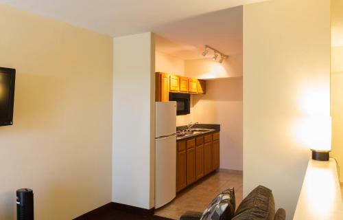 a small kitchen with a white refrigerator and cabinets at Marina Inn & Suites Chalmette-New Orleans in Chalmette