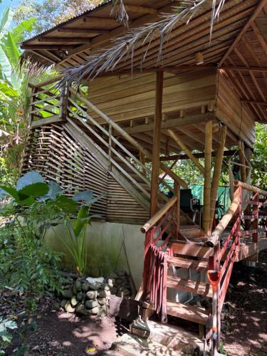 a wooden pergola with a bench in a garden at Orgánico Punta Riel in Cahuita