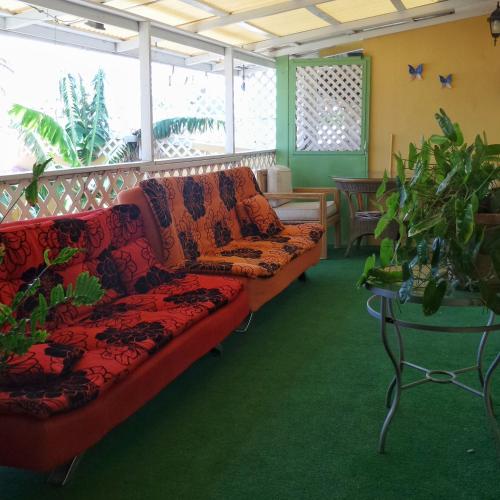 a red couch in a room with plants at A1 Apartments Aruba in Oranjestad
