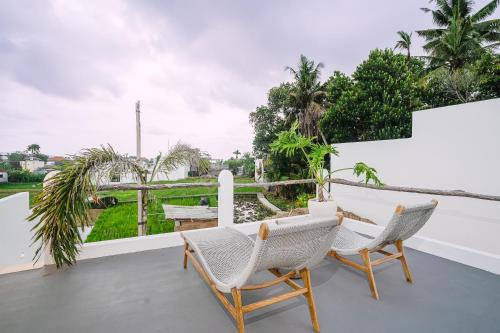 a patio with two chairs and a table on a balcony at Villa Alveena in Tumbak Bayuh in Tumbak Bayuh