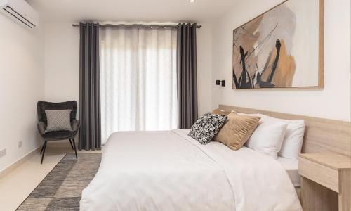 アクラにあるAmazing Two Bedroom Apartment Space Availableの大きな白いベッドと椅子のある寝室