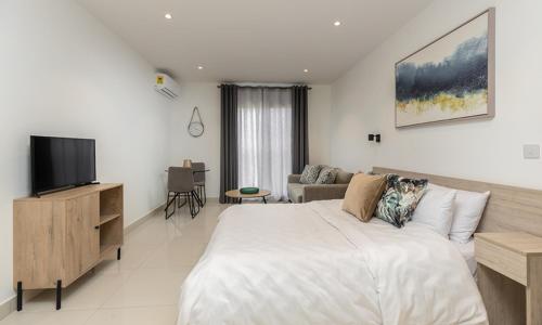 Un dormitorio blanco con una cama grande y un televisor. en Awesome 2 bedroom Space Available, en Accra
