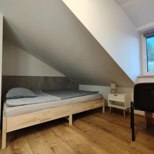 a bed sitting in a room under a stairs at Noclegi Pod Dębem in Wójtowo
