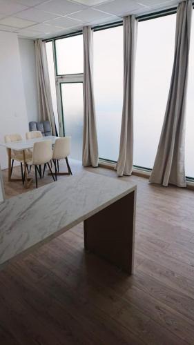 a living room with a table and chairs and windows at HYPER CENTRE AVEC JARDIN 47m2 COSY in Boulogne-sur-Mer