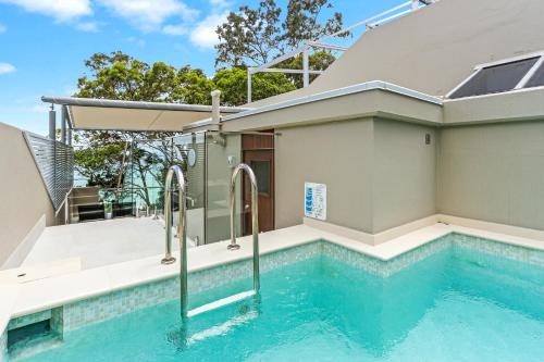 a swimming pool next to a house at Little Cove Court - Apt 5 Newly Renovated in Noosa Heads