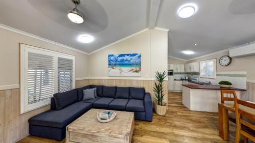 a living room with a blue couch and a kitchen at BIG4 Adventure Whitsunday Resort in Airlie Beach