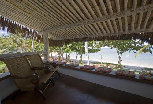 a porch with a chair and a view of the beach at Pousada Bendito Seja in Praia do Espelho